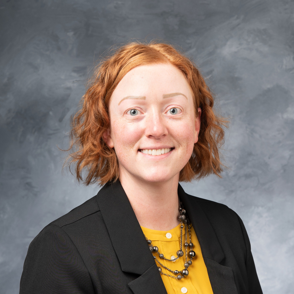 Professional photo of Rachel McGuire, a woman with red hair in a black blazer and gold top